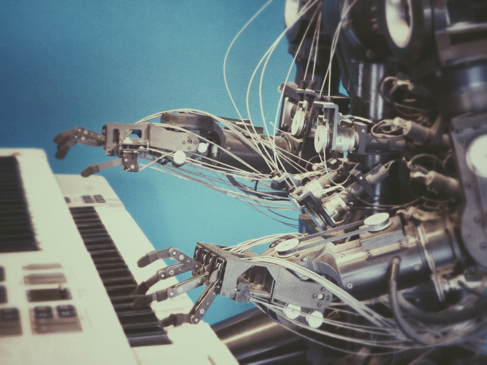 Robot a tocar piano blixtrombil malifluous Braços robóticos equipados com dedos posicionados acima de um teclado de piano, indicando uma máquina projetada para tocar ou aprender música melodiosa.